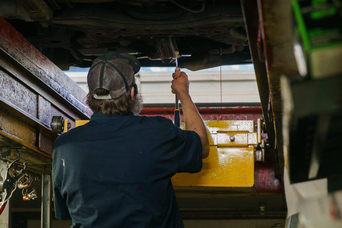 A technician servicing a vehicle on the lift in Astoria